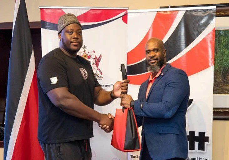TOP PERFORMANCE: World Para-Athletics silver medallist Akeem Stewart, left, collects a token from acting Permanent Secretary in the Ministry of Sport, Gabre Jesu McTair, upon his return at the Piarco International Airport, on Monday. (Image obtained at trinidadexpress.com)